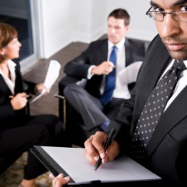 African American businessman, 40, making notes, co-workers conversing in background